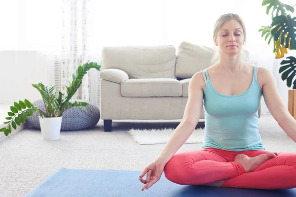 Beautiful chestnut practicing lotus pose on yoga mat indoor — Stock Photo, Image