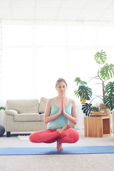 Schönes Weibchen balanciert in halber Lotus-Haltung auf Bunkern — Stockfoto