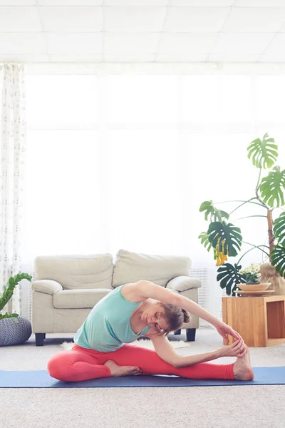 Beautiful female stretching in revolved head-to-knee pose — Stock Photo, Image