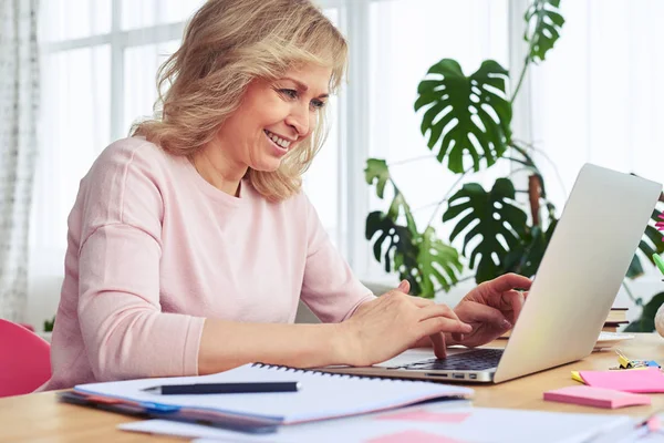 Alegre señora sonriendo y la impresión en el ordenador portátil —  Fotos de Stock