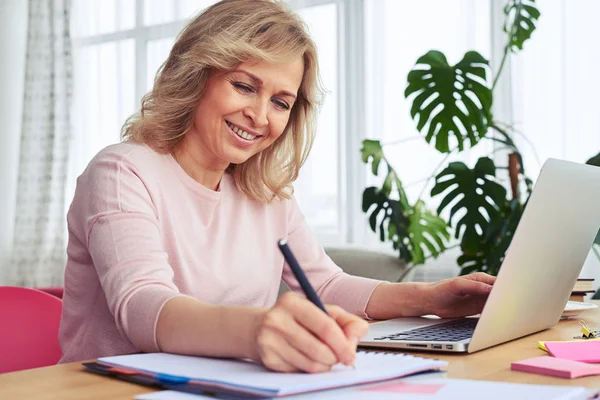 Sorridente donna premurosa scrivere mentre si lavora in computer portatile — Foto Stock