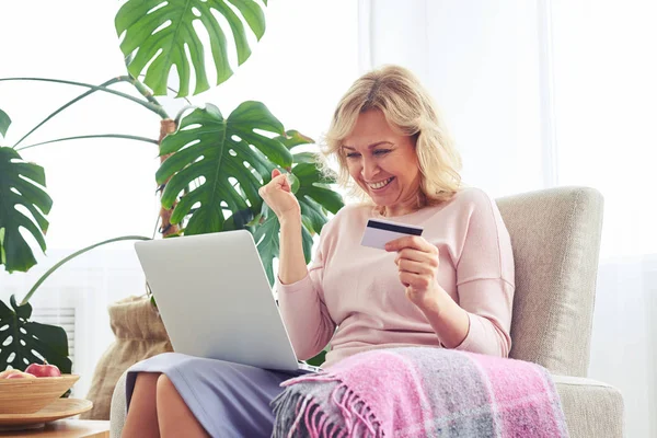 Smiling nice female holding credit card while working in laptop — Stock Photo, Image