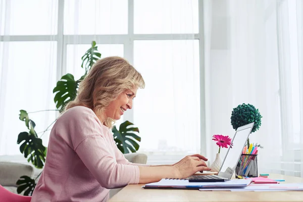 Lachende mevrouw werken in laptop in lichte kamer — Stockfoto