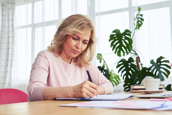 Señora concentrada bebiendo café mientras escribe —  Fotos de Stock