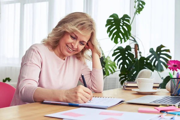 Gut aussehende Frau mit schönem Lächeln schreibt in Notizbuch — Stockfoto