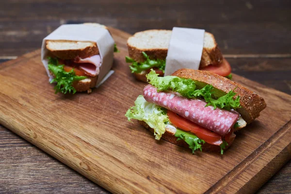 Two slices of lettuce and bread, one of sausage and tomato wrapp — Stock Photo, Image