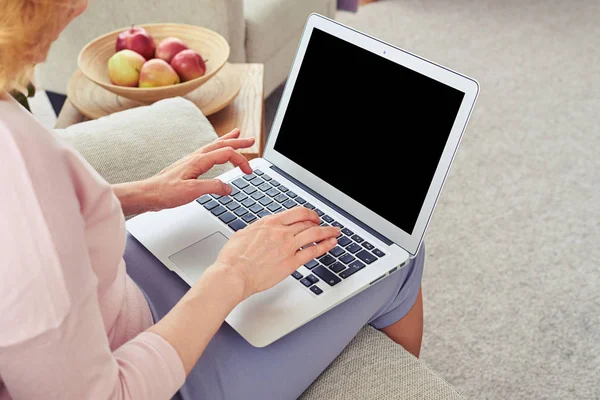 Mujer trabajando en el ordenador portátil mientras está sentado en el sofá acogedor en liv brillante —  Fotos de Stock