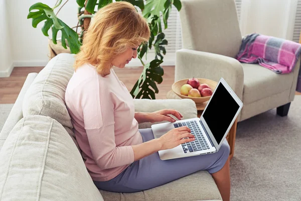 Vrij vrouwelijke werken in laptop zittend op de gezellige sofa — Stockfoto