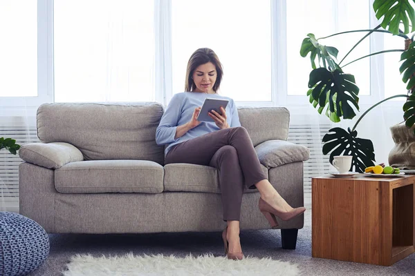 Koncentrerad vuxna kvinnliga arbetar i laptop medan du sitter på sof — Stockfoto