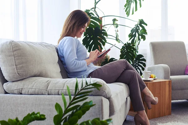 Gorgeous fru arbetar i laptop medan du sitter på soffan — Stockfoto