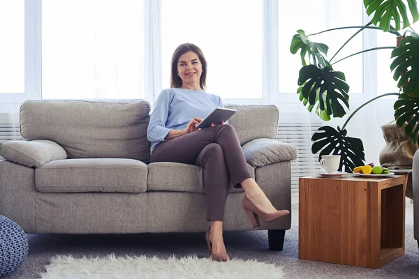 Charmiga brunett arbetar i laptop medan du sitter på soffan — Stockfoto