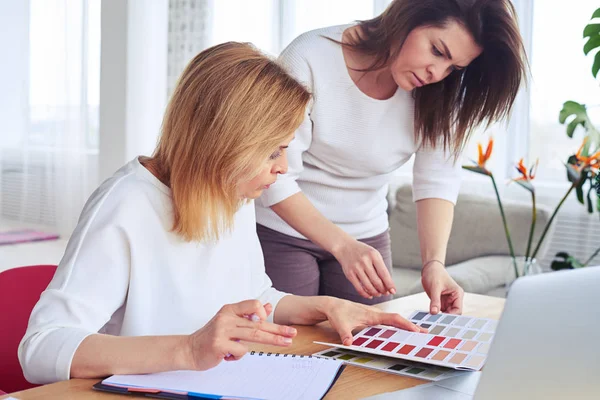 Graceful concentrated females looking through catalog of color p — Stock Photo, Image