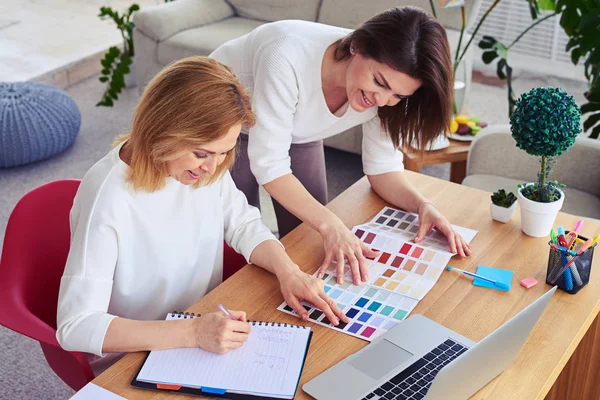 Twee sierlijke vrouwen werken met de catalogus van kleurenpalet — Stockfoto