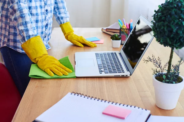 Woman dusting desk near laptop — Stock Photo, Image