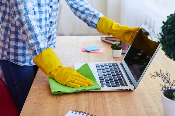 Vrouw in hemd en handschoenen afstoffen van laptop — Stockfoto