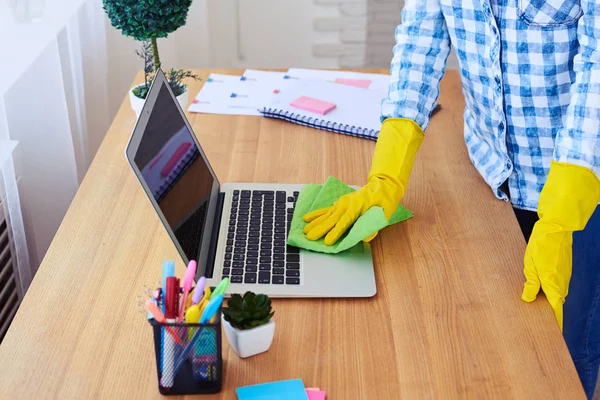 Slim girl dusting laptop standing on table — Stock Photo, Image