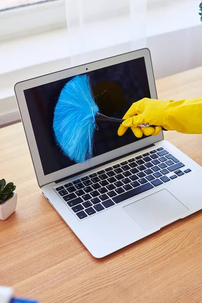 Vrouw in handschoenen afstoffen met kleine bezem laptop — Stockfoto