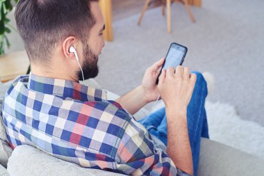 Sakallı adam akıllı telefon kullanarak kulaklık ile müzik