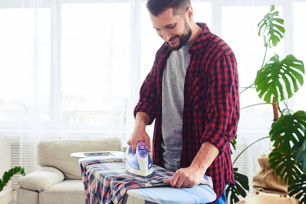 Handsome man ironing attentively clothes on board — Stock Photo, Image
