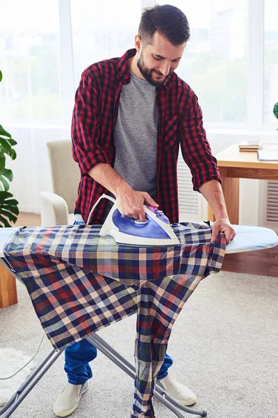 Good-looking dark man ironing attentively shirt on board — Stock Photo, Image