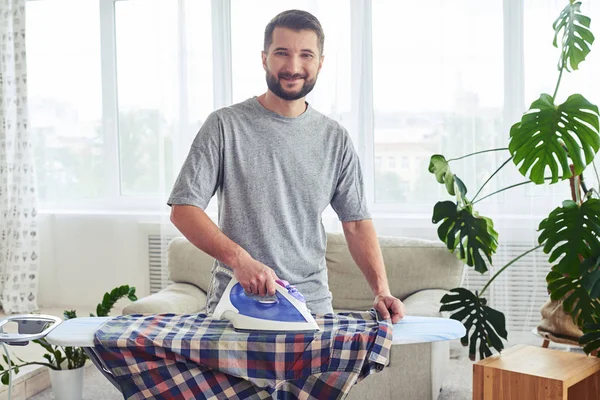 Lovely husband ironing attentively shirt on board — Stock Photo, Image