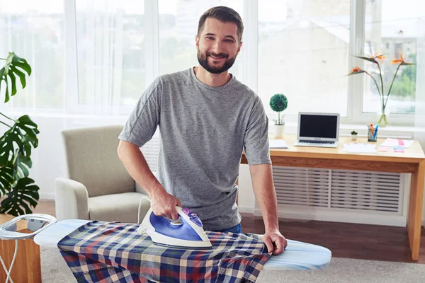 Pleased bachelor ironing diligently shirt on board — Stock Photo, Image