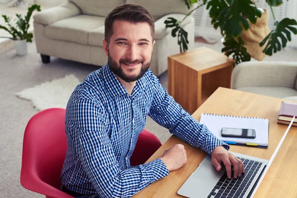 Attraktiver Mann sitzt am Tisch und arbeitet mit Laptop — Stockfoto