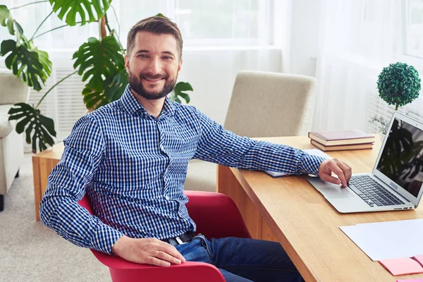 Herrlicher Herr sitzt am Tisch und arbeitet mit Laptop — Stockfoto