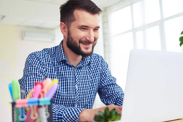 Agradável macho em azul camisa quadriculada trabalhando com laptop — Fotografia de Stock