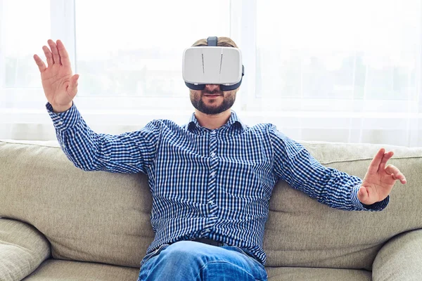 Pleasant man with beard working in VR glasses sitting on sofa — Stock Photo, Image