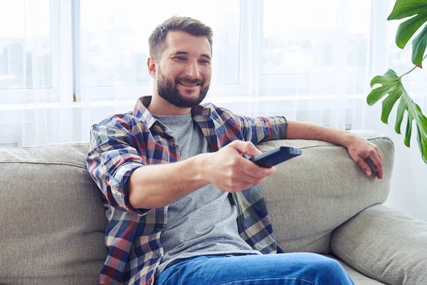 Bel ragazzo che cambia canale con telecomando — Foto Stock