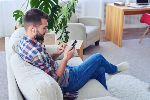 Stijlvolle man muziek beluisteren met koptelefoon met smartphone — Stockfoto