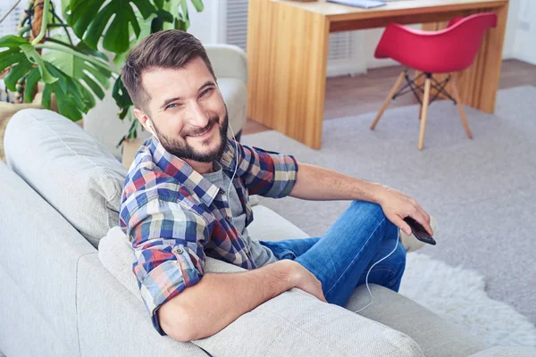 Tilltalande man lyssnar på musik med hörlurar och leende — Stockfoto