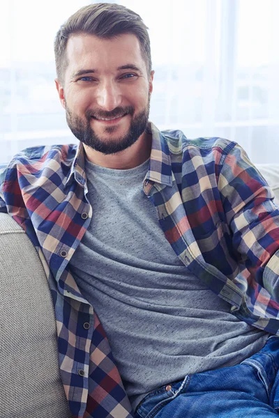 Man in geruite hemd leunend op rug oh sofa en rust — Stockfoto