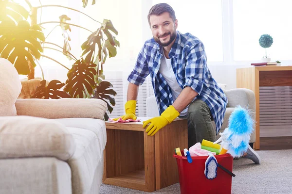 Esportivo masculino esfregando atentamente mesa de café — Fotografia de Stock