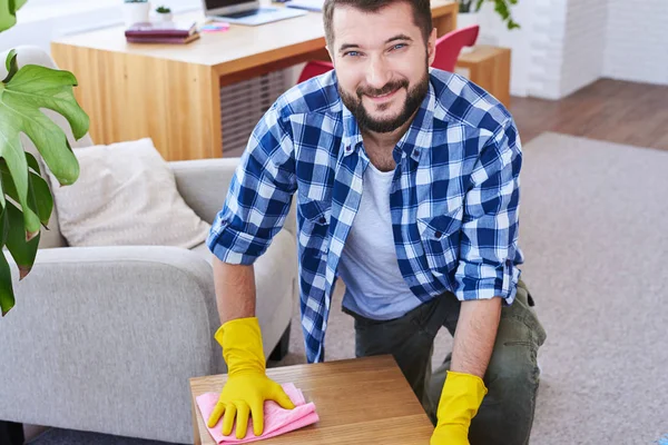 Handsome sir in gloves mopping coffee table — Stock Photo, Image