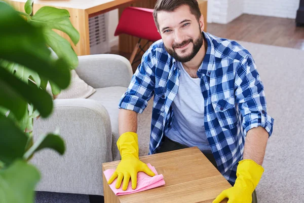 Stylish guy in gloves mopping coffee table — Stock Photo, Image