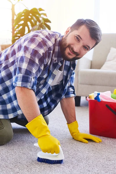 Hardworking sir in gloves brushing carpet — Stock Photo, Image
