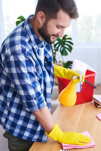 Caring guy pulverizing and dusting working place — Stock Photo, Image