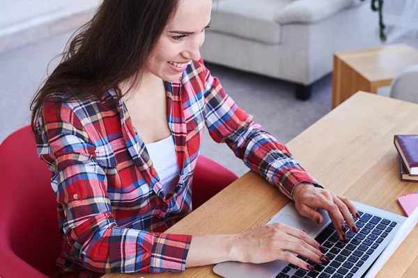 Ursnygg kvinna tejpning i laptop medan du sitter i skrivbord — Stockfoto