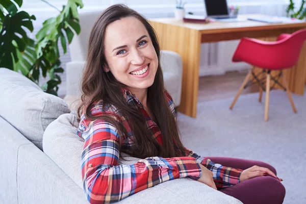 Happy female having rest sitting on stylish sofa