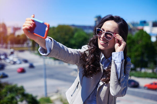 Привлекательный брюнет с селфи перед панорамой города

