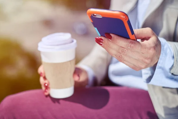 Frau surft im Handy und hält Tasse Kaffee in der Hand — Stockfoto
