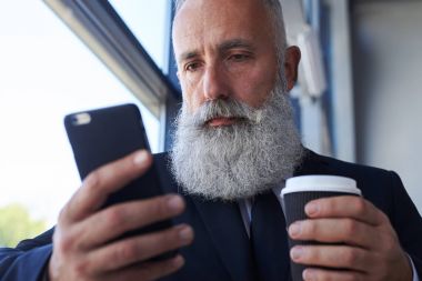 50-60 holding fincan kahve ve sörf yaşın pokerfaced adam