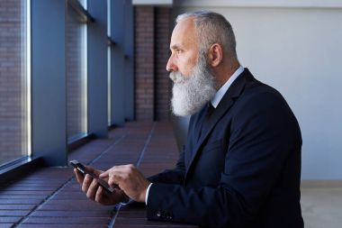 Korkunç erkek telefon çalışırken pencereden dışarı bakarak