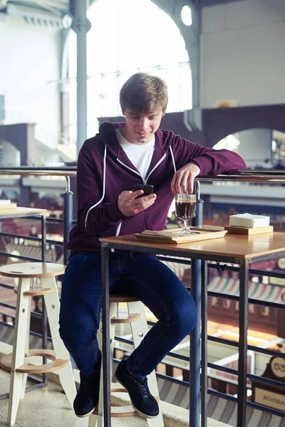 커피 한잔에 앉아 휴대 전화에서 서핑 하는 쾌적 한 남자 — 스톡 사진