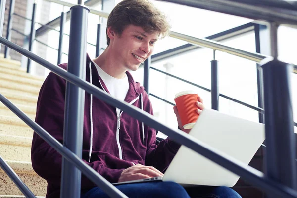 Agradável masculino segurando xícara de café e conversando no laptop — Fotografia de Stock