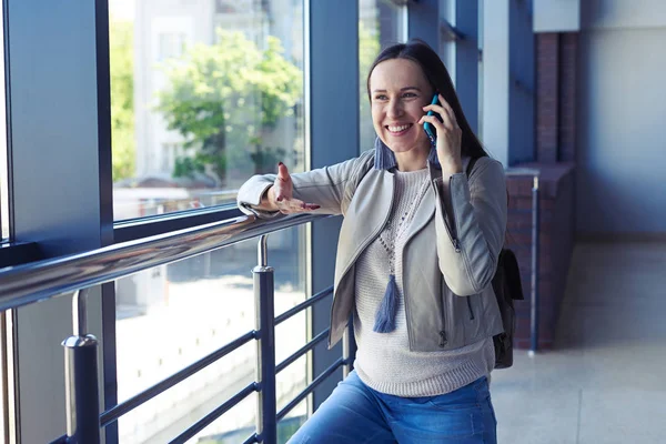 Emotionele dame praten over smartphone terwijl leunend op de leuning — Stockfoto