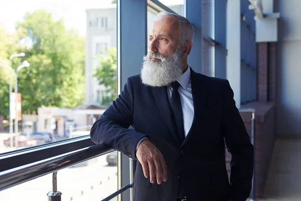 Età maschile non sorridente di 50-60 anni guardando fuori dalla finestra — Foto Stock