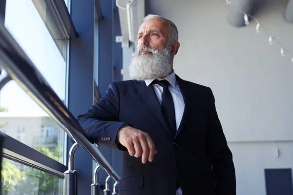 Концентрований джентльмен з сірою бородою, що дивиться у вікно — стокове фото